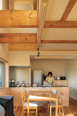 奥さんお気に入りの広々としたキッチンは、収納力のある造作棚のおかげでいつもスッキリ。住まいを支える古い梁と新しい梁が空間に味わいを与える。「新しい梁も経年とともに少しずつ色を増していくと藤井さんから聞いて、とても楽しみにしています」と奥さん